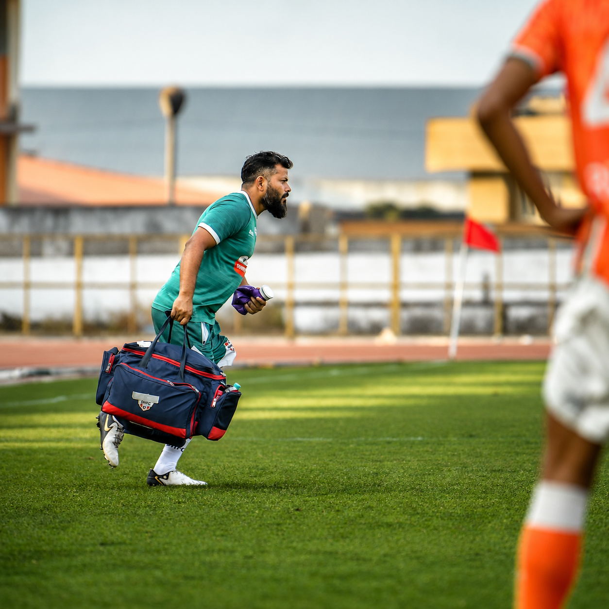 Sports physiotherapist running onto the pitch with a medical kit during a football match